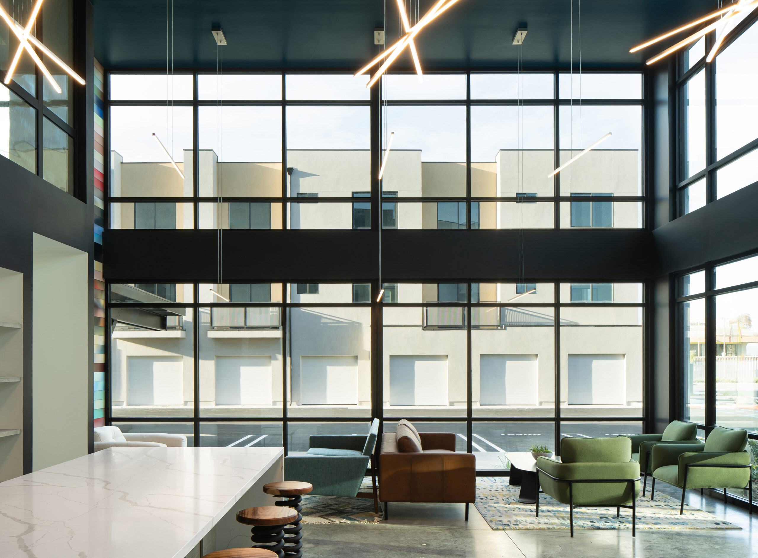 Interiors Photograph of Elements Apartments of Santa Maria, California. Main Lobby Area Showing floor to ceiling windows and apartments across the driveway around sunset