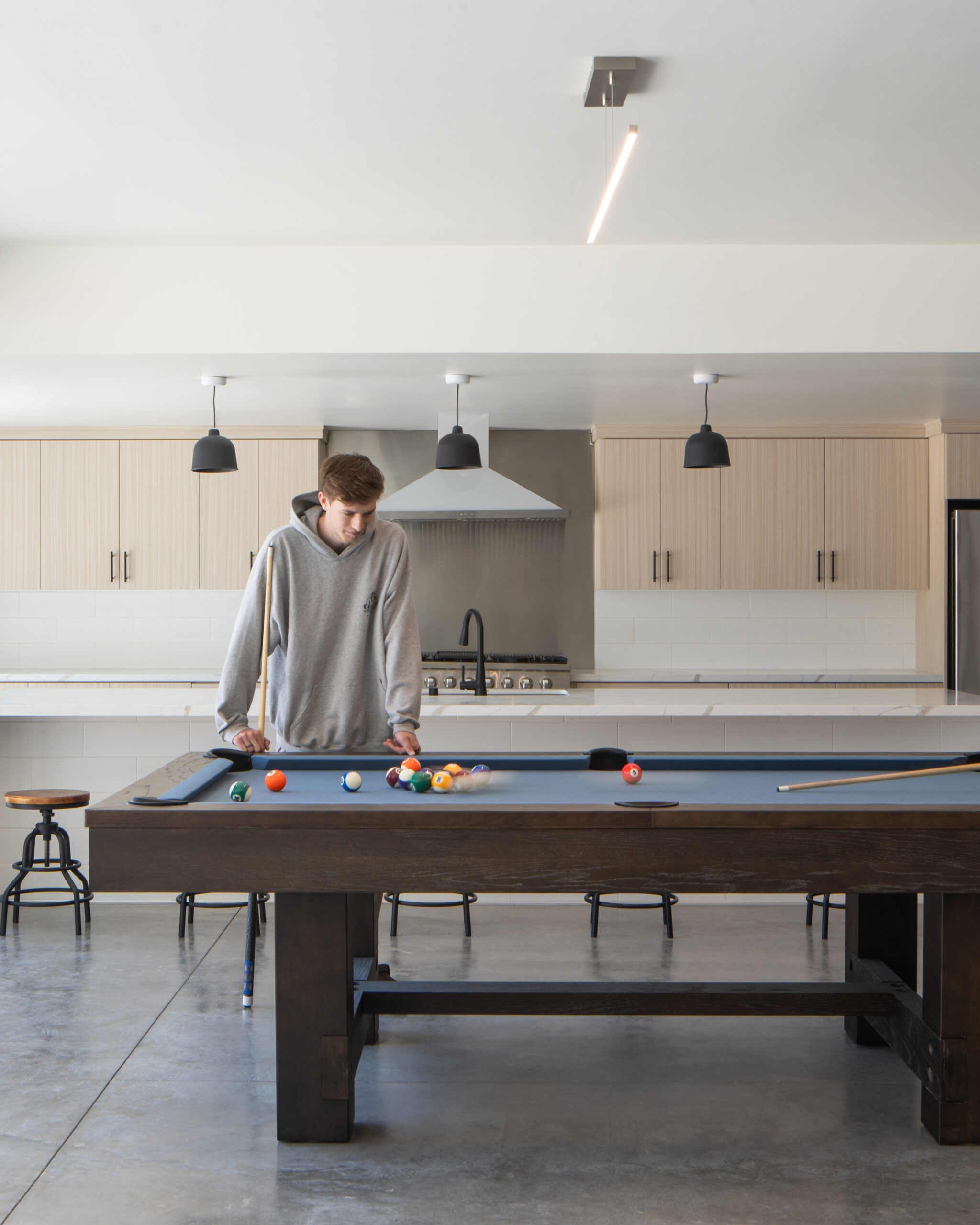Interior architectural photograph of the common kitchen area from Elements Apartments in Santa Maria, California. Includes models playing a game of pool
