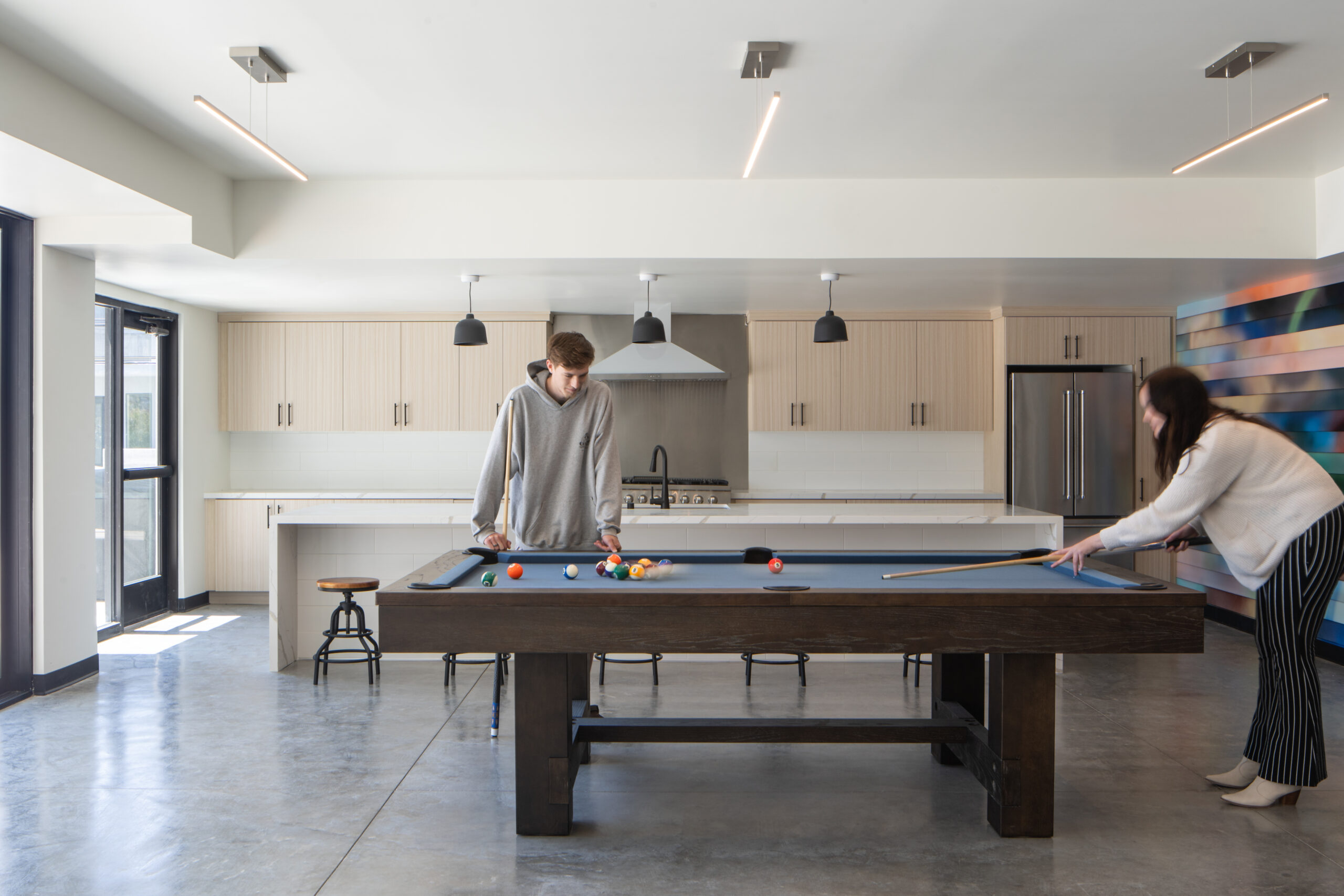 Interior architectural photograph of the common kitchen area from Elements Apartments in Santa Maria, California. Includes models playing a game of pool