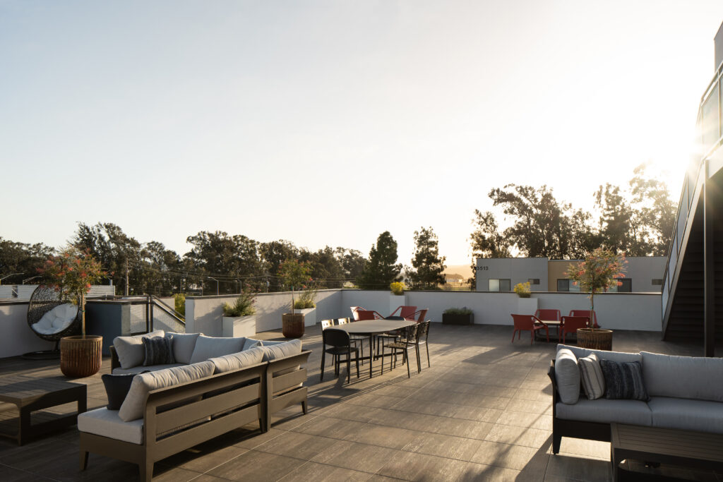 Exterior architectural photograph of a rooftop entertainment area at Elements Apartments around sunset, dramatic