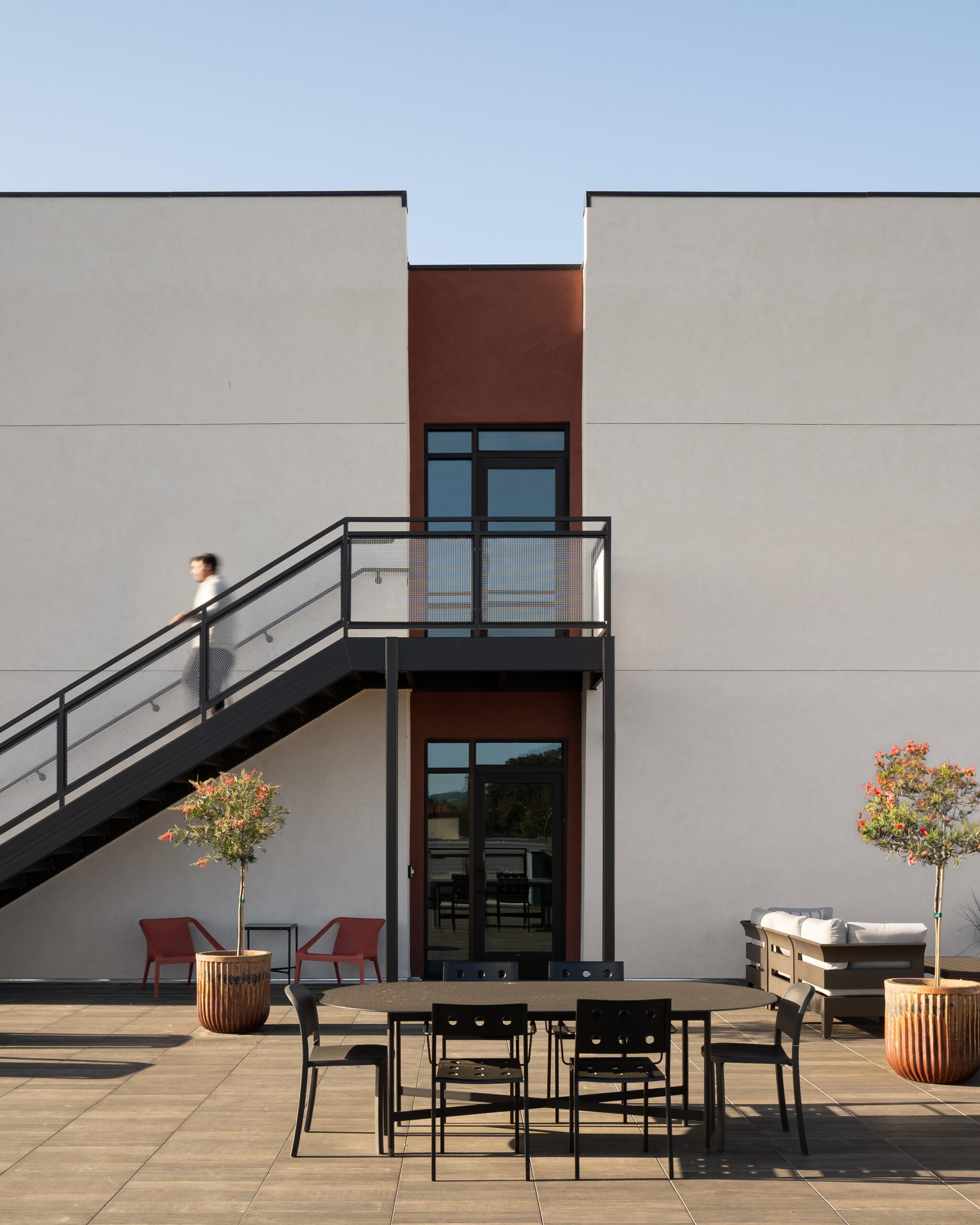 Exterior architectural photograph of a rooftop entertainment area at Elements Apartments around sunset, dramatic, model walking down stairs