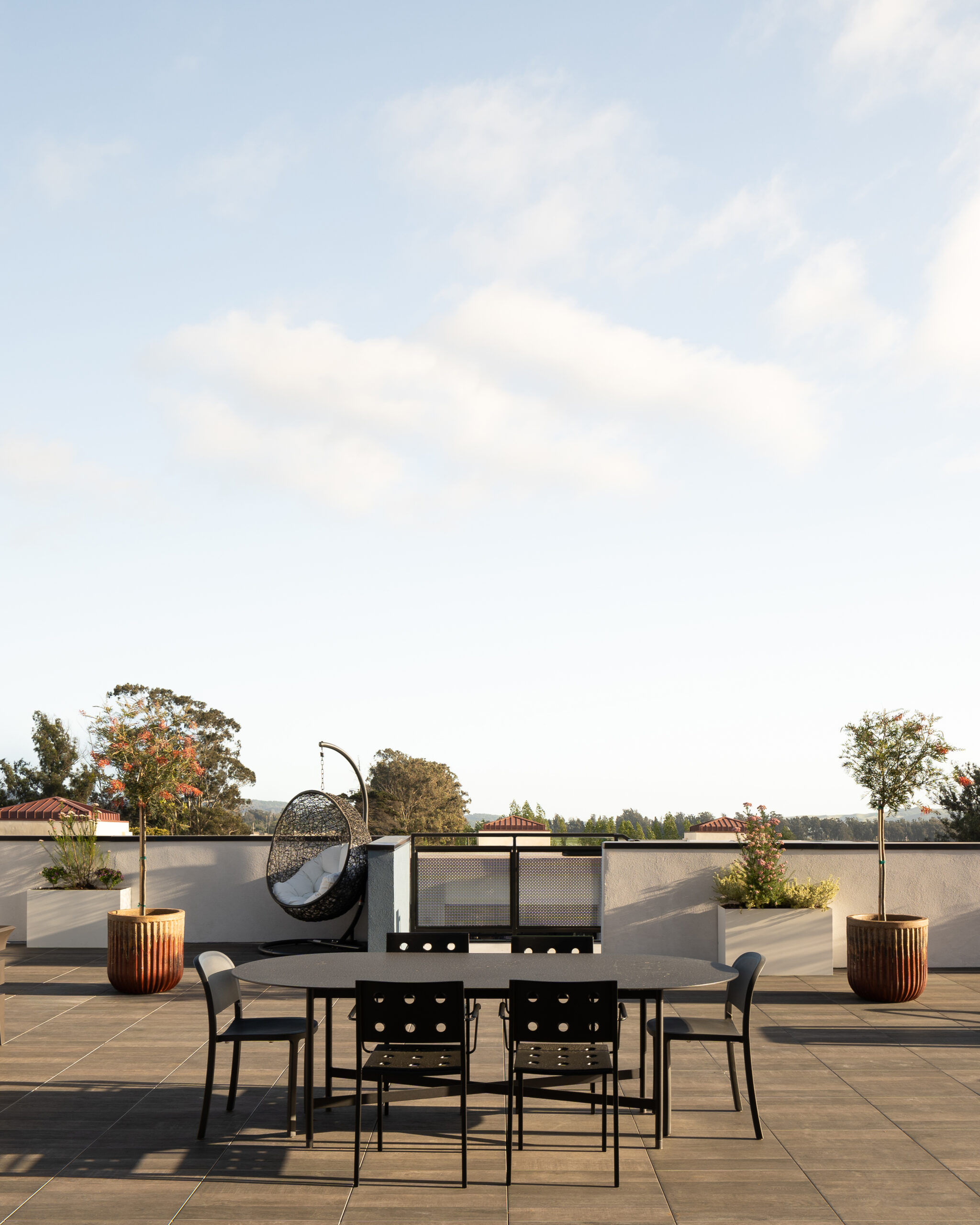 Exterior architectural photograph of a rooftop entertainment area at Elements Apartments around sunset, dramatic